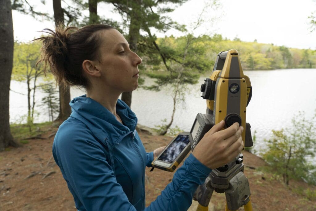 tara hartson using surveying equipment